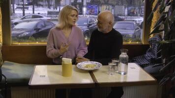 lindo idosos casal é conversando dentro cafeteria. estoque imagens de vídeo. idosos casal é conversando docemente em encontro dentro cafeteria. lindo casal em encontro dentro acolhedor cafeteria foto