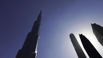 baixo ângulo Visão do burj Khalifa com azul céu atrás. Ação. moderno vidro fachada arranha-céu dentro a cidade Centro. foto