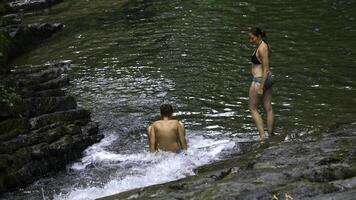 mulher e Adolescência Garoto tomando banho dentro espirrando cascata dentro tropical floresta. criativo. feliz família desfrutando fresco água a partir de fluindo cascata dentro selva. foto