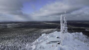 congeladas repetidor antena em a topo do uma Colina dentro inverno. grampo. aéreo Visão do inverno vale panorama e azul nublado céu. foto