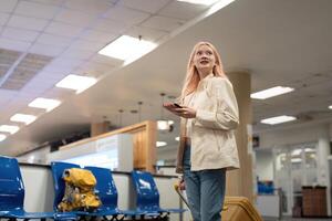 uma mulher ásia caminhando dentro a aeroporto. móvel, mala de viagem e viagem com uma jovem fêmea em a internacional viagem para trabalhos ou viagem foto