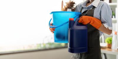 jovem mulher limpeza para desinfectar a escritório escritório limpeza funcionários limpeza empregada doméstica. fêmea limpador segurando uma balde com limpeza suprimentos foto