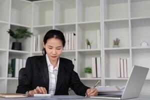 jovem o negócio mulher ásia ou empregado contabilidade escrituração contábil documentos verificação financeiro dados ou marketing relatório trabalhando dentro escritório com computador portátil. papelada gestão foto