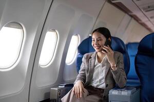 ásia jovem empresária bem sucedido ou fêmea empreendedor dentro formal terno dentro uma avião sentar dentro uma o negócio classe assento e usa uma Smartphone durante voo. viajando e o negócio conceito foto