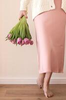 mulher dentro Rosa vestir segurando parte de cima baixa ramalhete do roxa tulipas foto