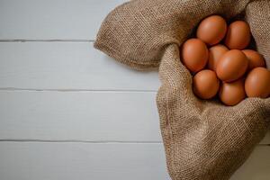 fresco frango ovos dentro uma cesta em uma saco, ovo dia, de madeira tabela.seletiva foco foto