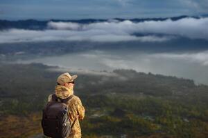 homem turista parece às a nascer do sol em a vulcão Batur em a ilha do blai dentro Indonésia. caminhante homem com mochila viagem em topo vulcão, viagem conceito foto