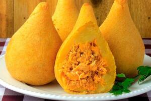 coxinha dentro a prato, tradicional brasileiro cozinha lanches recheado com frango, em rústico de madeira mesa foto