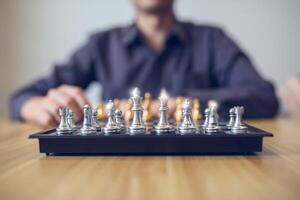 estratégico contemplação dentro açao com uma pessoa fazer uma xadrez mover, foco em a dourado e prata peças. o negócio estratégia sucesso conceito foto