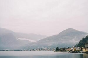 enevoado montanhas em a costa do lago como com luxo vilas. Itália foto