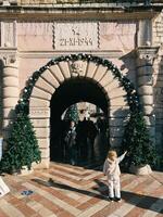 kotor, Montenegro - 25 dezembro 2022. pequeno menina carrinhos dentro frente do a antigo arco e pontos para uma decorado Natal árvore foto