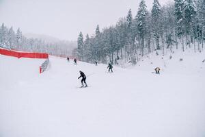 esquiadores descer a lado da montanha ao longo a vermelho cerca em a kolasin 1600 declive. Montenegro foto