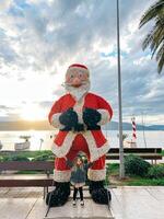 pequeno menina carrinhos perto a figura do santa claus em a passeio de a mar foto