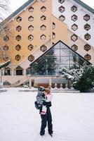 mãe com uma pequeno menina dentro dela braços carrinhos dentro frente do uma triangular hotel dentro a neve foto