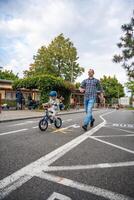 Praga, tcheco república - Outubro 10, 2023. jovem feliz pai ensina criança filha para passeio público bicicleta em tráfego Parque infantil dentro Praga, tcheco república, Europa. Alto qualidade foto