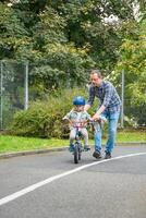 pai ensina criança filha para passeio público bicicleta em 1 do tráfego Parque infantil dentro Praga, tcheco república, Europa. Alto qualidade foto