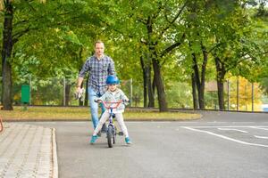 feliz família pai ensina criança filha para passeio público bicicleta em tráfego Parque infantil dentro Praga, tcheco república, Europa. Alto qualidade foto