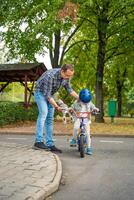 família pai ensina criança filha para passeio público bicicleta em 1 do tráfego Parque infantil dentro Praga, tcheco república, Europa. Alto qualidade foto