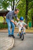 jovem pai ensina criança filha para passeio público bicicleta em 1 do tráfego Parque infantil dentro Praga, tcheco república. Alto qualidade foto