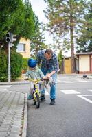 feliz família pai ensina criança filha para passeio público bicicleta em 1 do tráfego Parque infantil do Praga, tcheco república, Europa. Alto qualidade foto