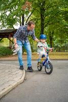 jovem pai ensina criança filha para passeio público bicicleta em 1 do tráfego Parque infantil dentro Praga, tcheco república, Europa. Alto qualidade foto