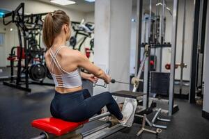 jovem esporte mulher vestindo esporte vestem fazendo exercício com ginástica equipamento às academia, ela exercício para Forte costas e Boa saudável. Alto qualidade foto