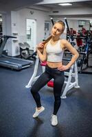 jovem desportivo mulher vestindo roupa de esporte posando antes fazendo exercício com ginástica equipamento às academia, ela exercício para Forte e Boa . Alto qualidade foto