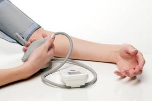 sangue pressão medição. mulher mãos com tonômetro em branco fundo. foto