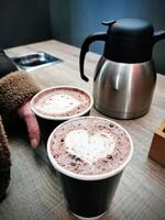 fechar-se do fêmea mão segurando café café com leite com lareira em forma decorado espuma em principal, expresso remover, bebidas e bebidas, foto