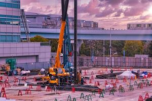 uma crepúsculo do guindastes às a debaixo construção perto a estrada de ferro telefoto tiro foto