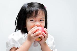 criança comia uma maçã vermelha com gosto. fundo branco isolado. foto