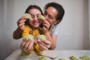 mãe e filha jogando juntos dentro a cozinha, tendo Diversão enquanto desfrutando cozinhando caseiro dumplings para família jantar foto