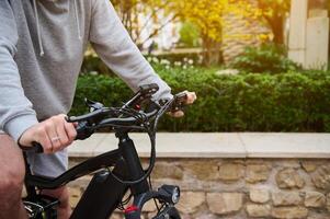 fechar-se homem equitação elétrico bicicleta às pôr do sol. bicicleta partilha cidade serviço. homem alugando eco urbano público transporte foto