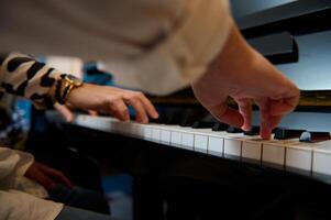 músico Garoto jogando grande piano durante música lição, realizando clássico melodia, criando e sentindo-me a ritmo do sons enquanto colocando dedos em branco e Preto piano chaves. fechar-se inferior visualizar. foto