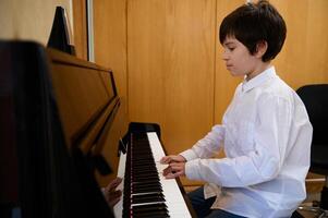 autêntico retrato do bonito Garoto músico pianista realizando clássico melodia, praticando acorde musical instrumento foto