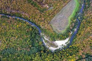 aéreo Visão a partir de zangão do a rio através montanha colinas com outono árvores foto