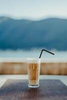 vidro do frappe com uma Palha em uma mesa dentro uma cafeteria foto