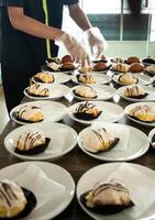 hotel empregados estão preparando lanche bolos em pratos antes a reunião. muitos linhas do pratos com bufê lanches. foto