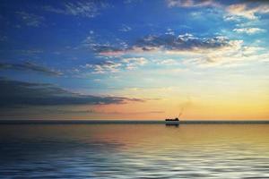 um navio solitário no horizonte no mar ao pôr do sol. foto