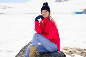 jovem sentada em uma rocha nas montanhas nevadas no inverno, em sierra nevada, granada, espanha.