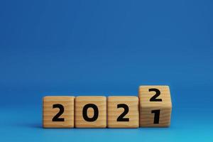 início ao ano 2022. bloco de cubo de madeira lançando para alterar o ano de 2021 para o ano de 2022 em fundo azul com espaço de cópia. conceito de feliz ano novo. Ilustração 3D render. foto