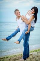 cara e uma garota de jeans e camiseta branca na praia foto