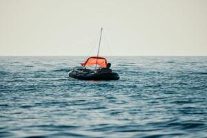 pescador mar barco. turista manobrando a inflável barco enquanto pescaria dentro uma vida jaqueta, com a lindo pôr do sol mar dentro a fundo. uma relaxante pescaria viagem. foto