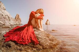 mulher viagem mar. feliz turista dentro vermelho vestir apreciar levando cenário ao ar livre para recordações. mulher viajante posando em a Rocha às mar baía cercado de vulcânico montanhas, partilha viagem aventura viagem foto