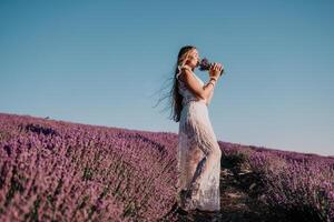 mulher lavanda campo. feliz despreocupado mulher dentro uma branco vestir caminhando dentro uma lavanda campo e cheirando uma lavanda ramalhete em pôr do sol. ideal para caloroso e inspirado conceitos dentro desejo de viajar e viagem. foto