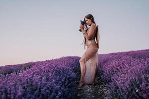 mulher lavanda campo. feliz despreocupado mulher dentro bege vestir e chapéu com ampla borda cheirando uma florescendo lavanda em pôr do sol. perfeito para inspirado e caloroso conceitos dentro viagem e desejo de viajar. fechar acima foto