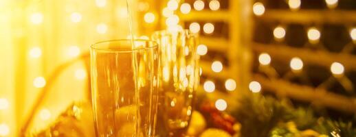dois champanhe óculos preenchidas com champanhe estão colocada em uma mesa com uma fruta arranjo. a óculos estão cercado de luzes, criando uma festivo atmosfera. foto