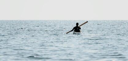 mulher mar caiaque. feliz sorridente mulher dentro caiaque em oceano, remar com de madeira remo. calma mar água e horizonte dentro fundo. ativo estilo de vida às mar. verão período de férias. foto