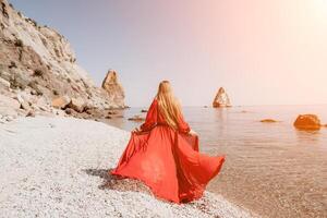 mulher viagem mar. feliz turista dentro vermelho vestir apreciar levando cenário ao ar livre para recordações. mulher viajante posando em a Rocha às mar baía cercado de vulcânico montanhas, partilha viagem aventura viagem foto