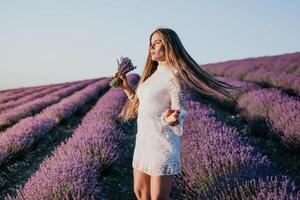 mulher lavanda campo. feliz despreocupado mulher dentro uma branco vestir caminhando dentro uma lavanda campo e cheirando uma lavanda ramalhete em pôr do sol. ideal para caloroso e inspirado conceitos dentro desejo de viajar e viagem. foto